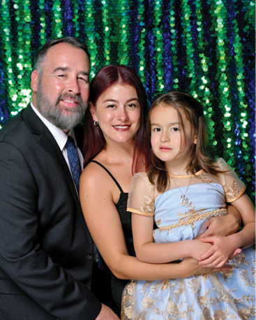 A man, woman, and girl are posing for a picture.

Description generated by AI