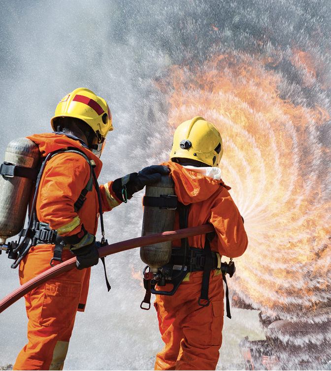 Two firefighters water spray by high pressure nozzle in fire fighting operation / Fire and rescue training school regularly to get ready.