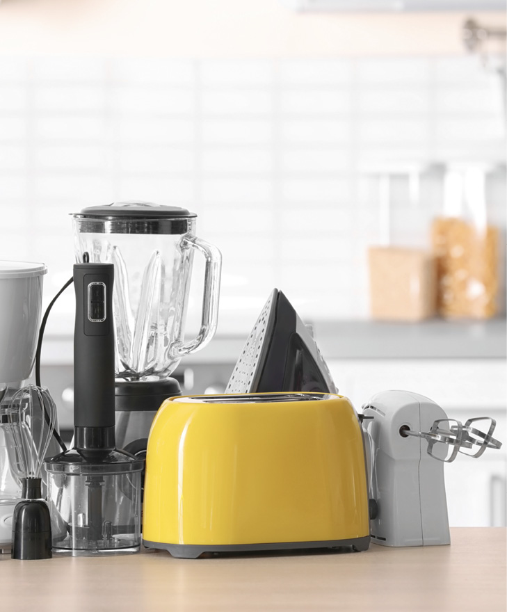 Household and kitchen appliances on table against blurred background.
