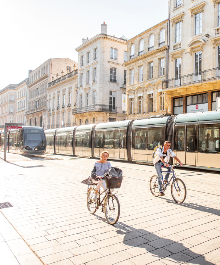 BORDEAUX, FRANCE - May 24, 2017: Street view with people ride a bicycles and modern trams in Bordeaux city during the morning in France.