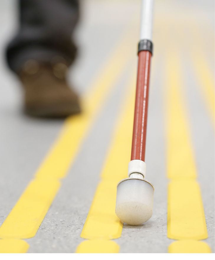 Blind pedestrian walking and detecting markings on tactile paving with textured ground surface indicators for blind and visually impaired. Blindness aid, visual impairment, independent life concept.