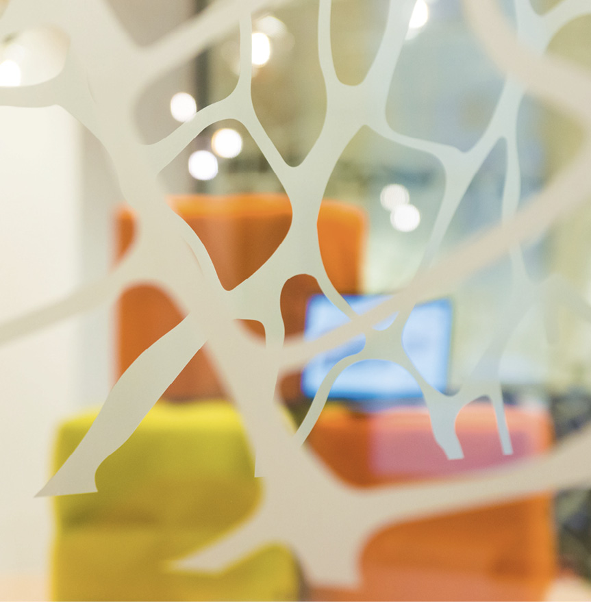 Image of CCMC offices in Brussels, with a computer and three coloured boxes behind a decorated glass.