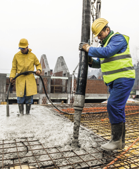 A construction worker control a pouring concrete pump on construction site and sunset background.