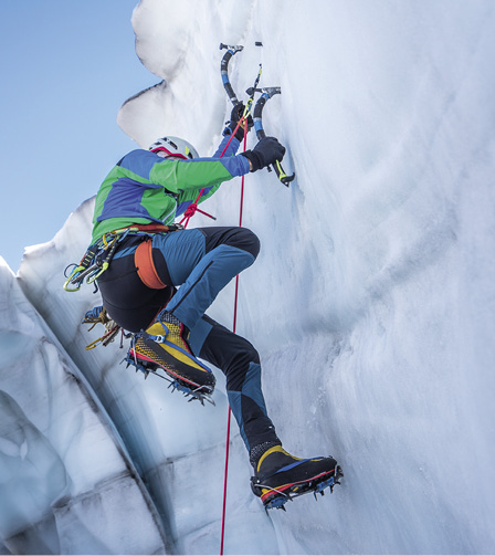 Epic shot of an ice climber climbing on a wall of ice. Mountaineer and climber on an adventure extreme ascent with ice axe and crampons. Alpine extreme climbing on a serac or crevasse.
