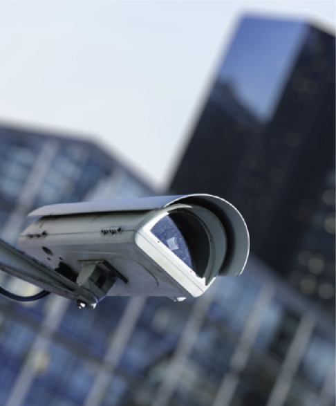 A cctv security camera in a city with blury business building on background.