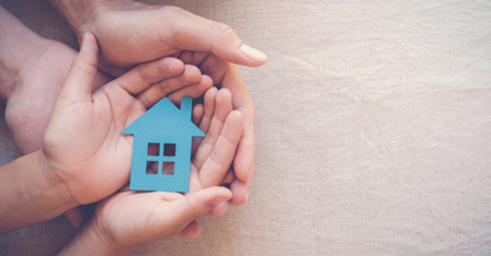 Adult and child hands holding paper house, family home, homeless housing and home protecting insurance concept, international day of families.