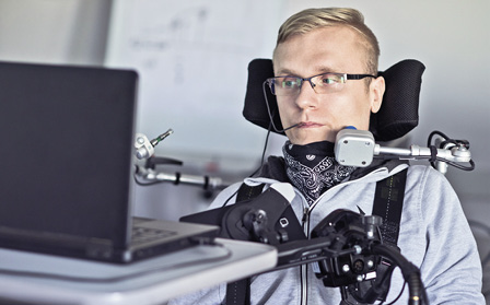 Disabled student in class room working with laptop.